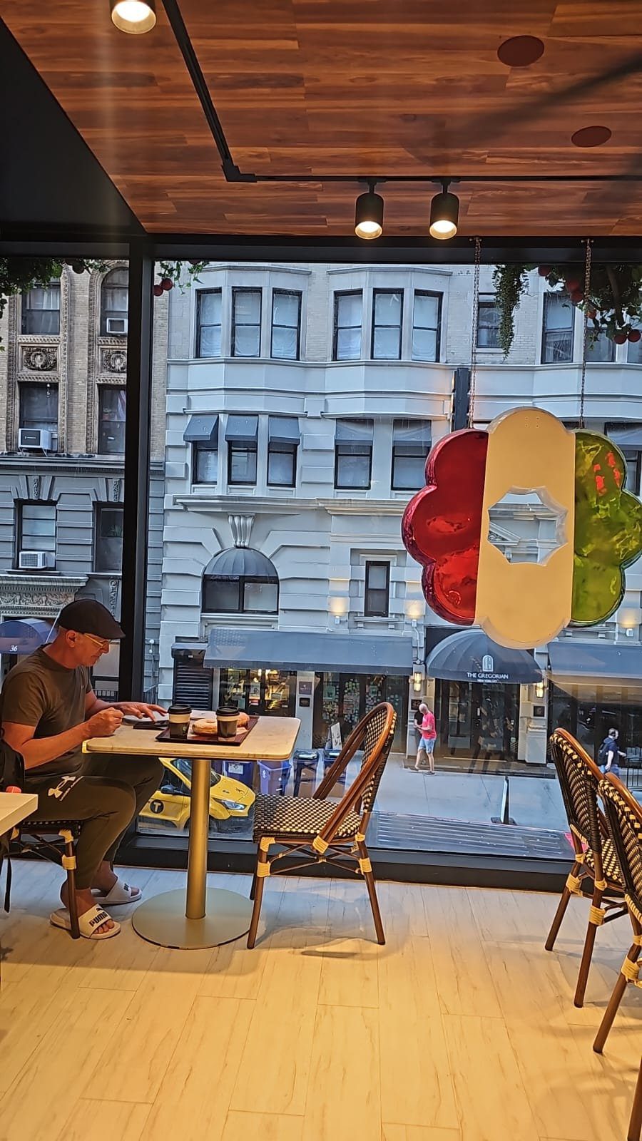 Luca Scainelli al tavolo di un bar a Manhattan con donut e caffè davanti alla vetrina sulla strada