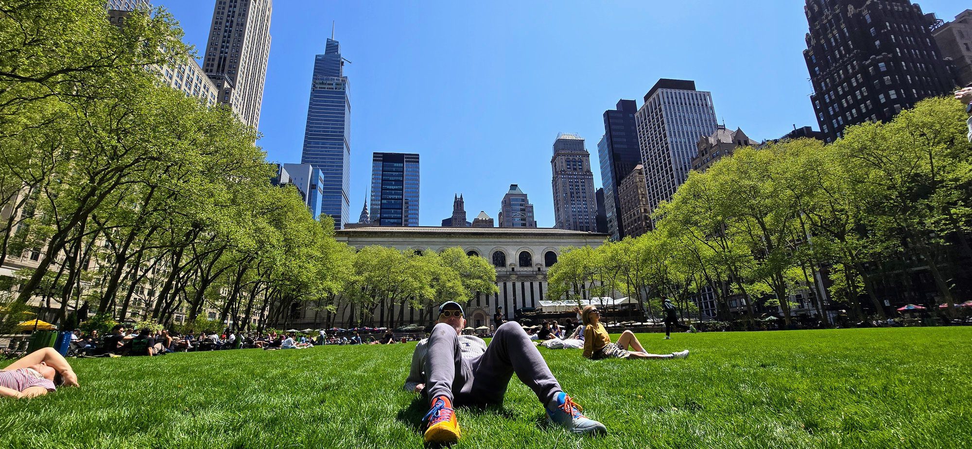 Luca Scainelli sull'erba di Bryant Park a Manhattan con lo skyline di New York sullo sfondo