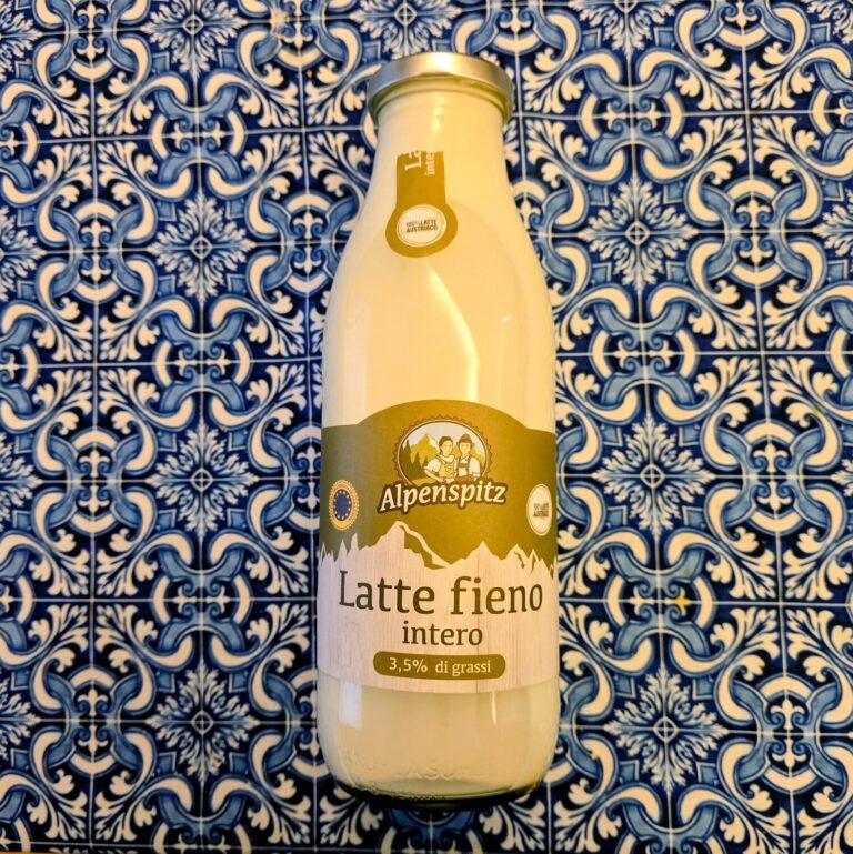 Bottiglia di latte fieno intero Alpenspitz su sfondo di mattonelle blu