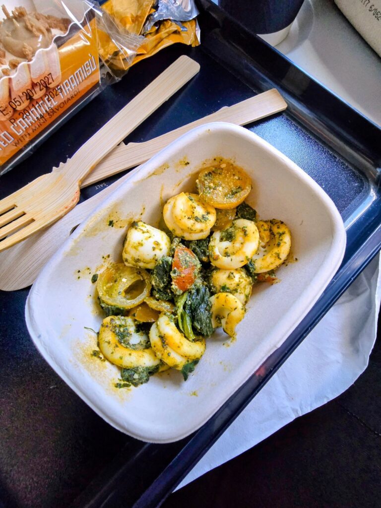Tortellini al pesto con spinaci e pomodorini serviti su vassoio Delta Airlines Didascalia: Pasta al pesto Delta Airlines. Il viaggio inizia così