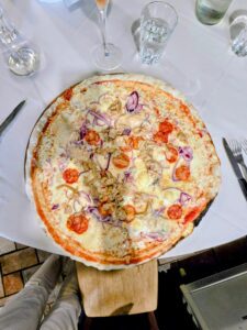 Pizza Esagerata vista dall'alto su tagliere di legno, con zola, taleggio, salame piccante, porcini e cipolla rossa, alla Trattoria da Diego di Palazzolo sull'Oglio