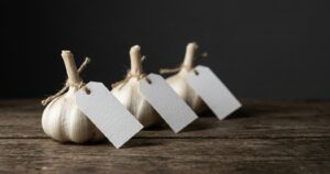 Tre teste d'aglio con cartellino vuoto appeso, senza varietà né provenienza: l'aglio si assaggia sempre alla cieca